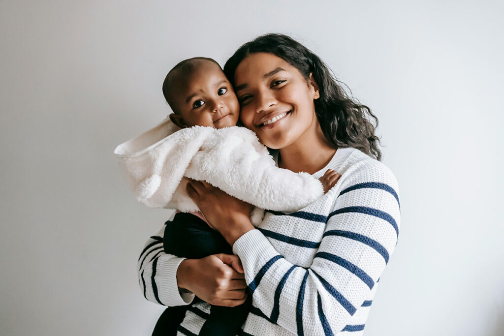Young mother holding her happy toddler close to her and smiling.